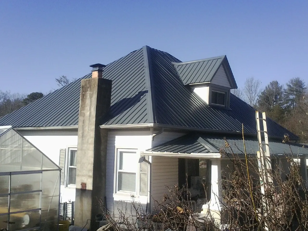 Dark blue standing seam metal roof on a white farmhouse with dormer — Slate & Tile Roof Repair by Roofing Brothers in Canoga Park