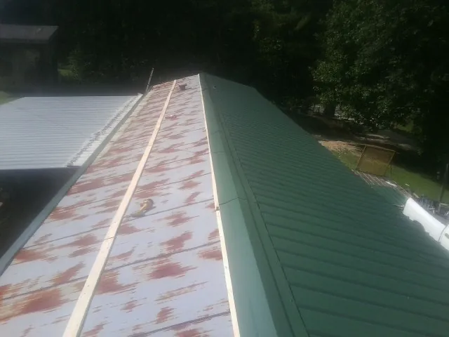Old rusted panels beside newly installed green metal roofing — Wind Damage Roof Repair by Roofing Brothers in Canoga Park