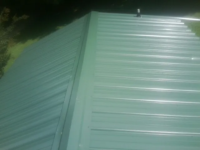 New green metal panels meeting at the ridge of a roof — Flat Roof Repair work by our crew in Canoga Park