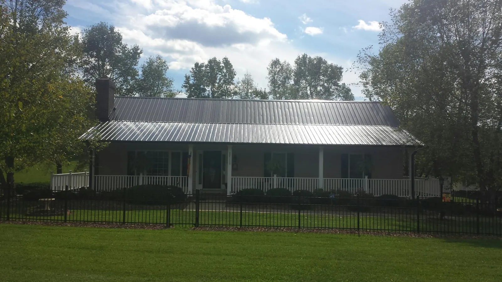 Gray metal roof on a brick ranch with a full width front porch — Gutter Guard Installation work by our crew in Canoga Park