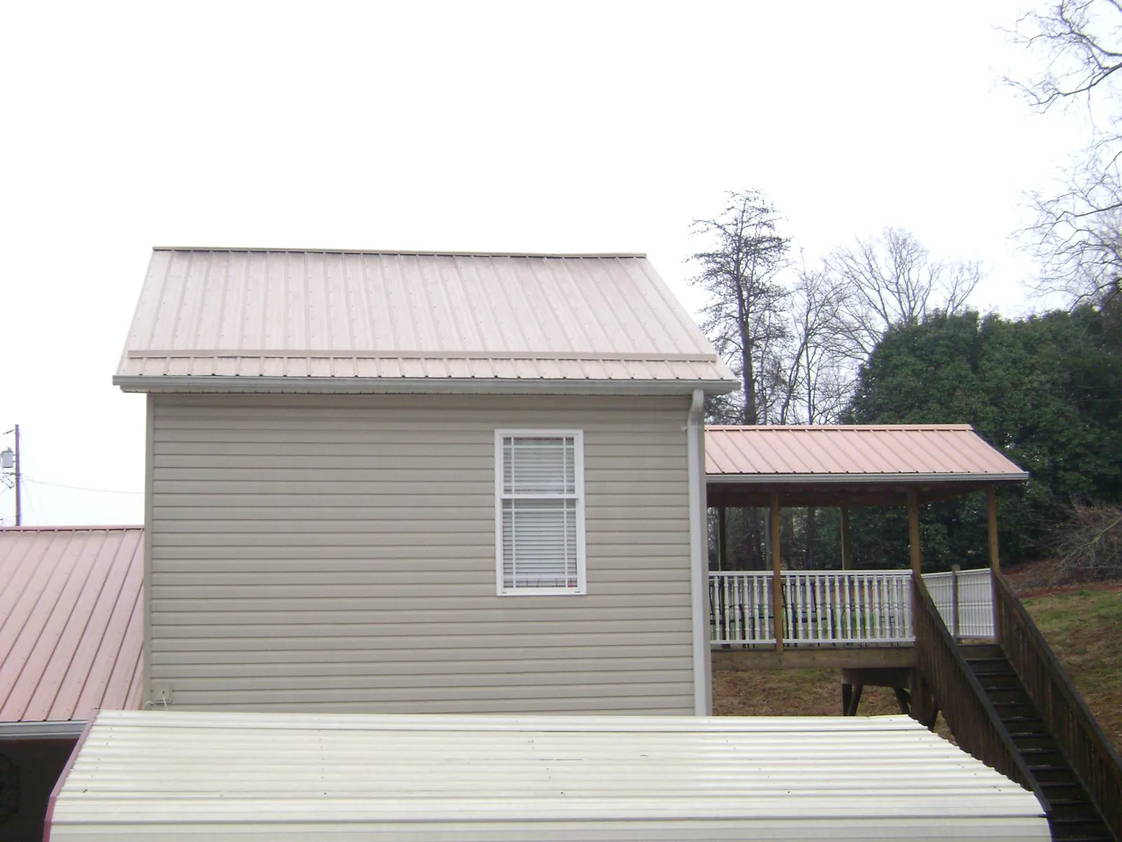 Tan metal roofs on a two story addition and attached porch, from a Roof Replacement job in Canoga Park