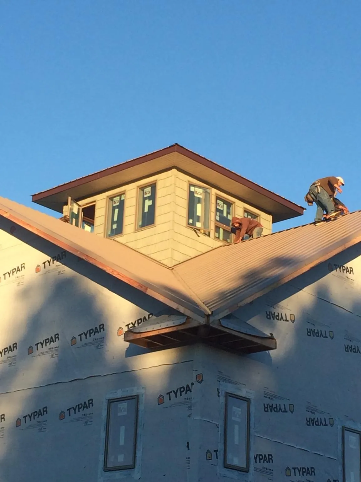 Roofers working around a rooftop cupola on a new metal roof at sunset — Roof Waterproofing in Canoga Park by Roofing Brothers